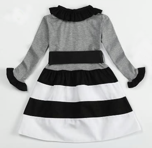 Black, grey and white long sleeved dress with ruffle sleeaves and collar. A thick ribbon slides around the waist and ties in a big bow. 