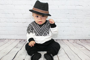 Two piece toddler boy sweatsuit. Long sleeve black and white designed top with black comfy pants with an elastic waist. 